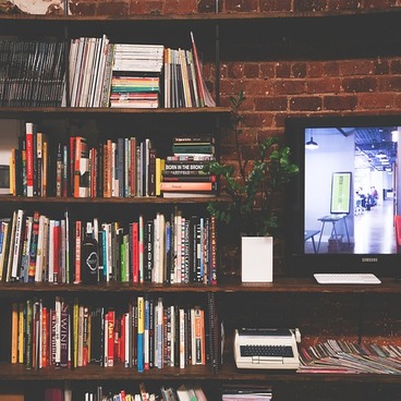 Une bibliothèque avec des étagères remplies de livres et un écran de télé allumé